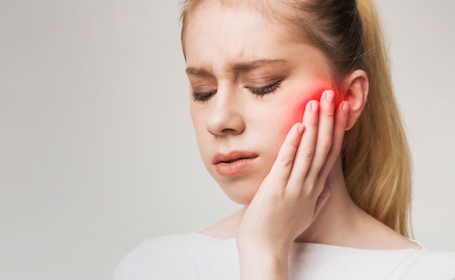 A woman holding her jaw in pain.